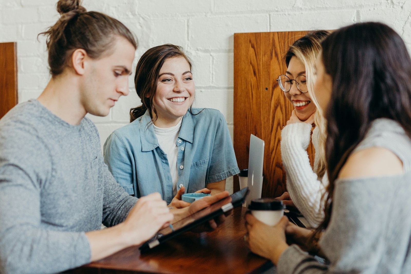 Vier junge Fachleute um einen Laptop in einer Coaching-Sitzung in kleiner Gruppe
